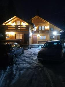 亚霍里纳Ski Chalet Jahorina的两辆汽车在晚上停在雪地的房子