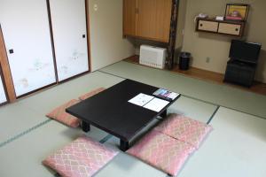 富士河口湖山田日式旅馆的一间设有一张桌子和两个粉红色垫子的房间
