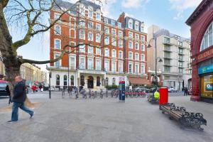 伦敦London Choice Apartments - Gloucester Road - Kensington的一个人在建筑物前的街道上行走