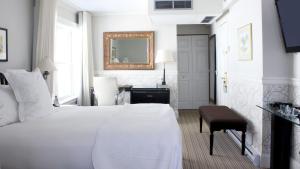 北哈特利Manoir Hovey, Relais & Châteaux的白色卧室配有床和镜子