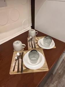 伦敦Luxury Cosy Retreat Apt的桌子上放有盘子和杯子,餐具