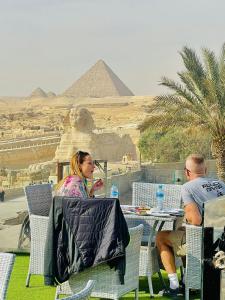 开罗White House Pyramids View的两个坐在金字塔前桌边的人