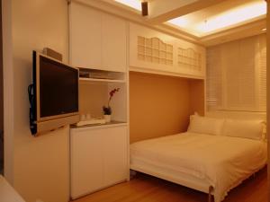 香港名樂居 At The Eden的一间小卧室,配有一张床和一台平面电视