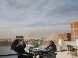开罗Eagles Pyramids View的两个坐在桌子上,拍金字塔的照片