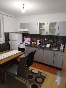 萨拉热窝Apartman Leki的厨房配有白色橱柜和桌椅