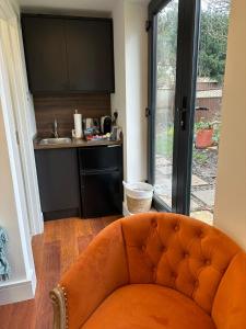 亨顿Bespoke Gallery guesthouse的带厨房的客房内的橙色沙发