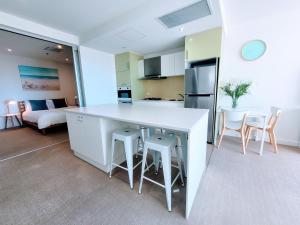 格莱内尔格CityViews @ Glenelg * Pool/Beach * Free Parking *的厨房以及带白色柜台和椅子的客厅。