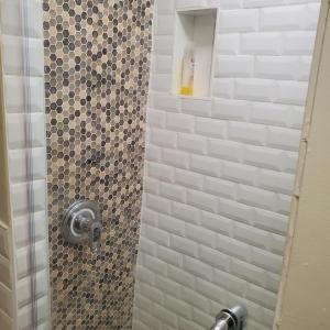 布朗克斯STUDIO and ONE BEDROOM APARTMENTS的带淋浴和瓷砖淋浴的浴室