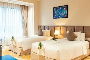 顺化La Vela Hue Hotel的配有白色床单的酒店客房内的两张床