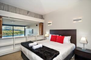 皇后镇Pure Retreat Lake View的一间卧室配有一张带红色枕头的大床和窗户