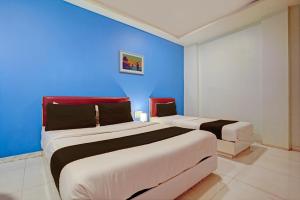 孟买OYO Hotel Blue Sea Near Chhatrapati Shivaji International Airport的蓝色墙壁客房的两张床