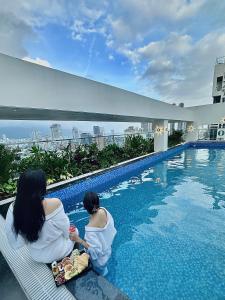 岘港ViAn Hotel And Spa Danang的两个女人坐在游泳池旁边