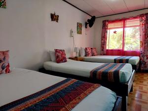 托尔图格罗Chinitas Eco Lodge的带三张床和窗户的客房