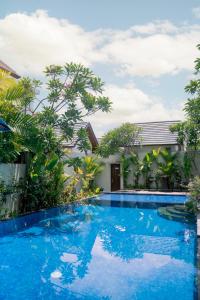 库塔The Calna Villa Bali的一座树木繁茂的房屋前的游泳池
