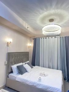 马尼拉Grace Residences Elevate Escapes的卧室配有一张带吊灯的大型白色床。