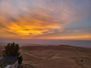 ‘ĀbilAl Namteh Lodge的山丘上一座建筑的日落
