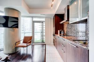 多伦多Downtown Toronto APT的厨房配有木制橱柜和椅子