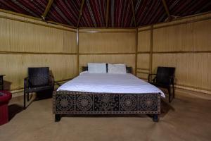 Al WāşilSAFARI-Glamping的卧室配有一张床,卧室配有两把椅子