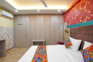 KakarmathaFabHotel RS Residency的一间卧室配有一张床,墙上挂着绘画作品