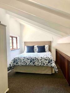德班Sherwood Garden Cottage的一间卧室配有一张带蓝色枕头的床