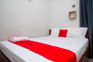 日惹RedDoorz Syariah near Pascasarjana UGM 3的卧室配有红色毯子,位于床上