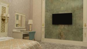 撒马尔罕DiliMah Premium Luxury的一间卧室配有一张床和一张书桌,墙上配有电视