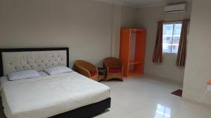 北干巴鲁IHomestay Pekanbaru的一间卧室配有一张床、两把椅子和一个窗户