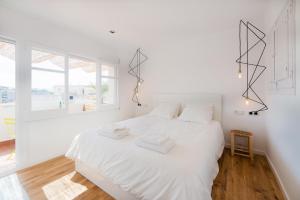 布拉内斯Apartamento Corall的白色的卧室设有白色的床和窗户。