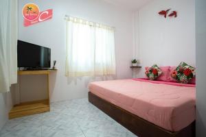 丽贝岛Tamtawan Guesthouse - ตามตะวันเกสเฮ้าส์的卧室配有粉红色的床和平面电视。