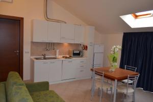 里米尼Residence Ducale的厨房配有白色橱柜、桌子和桌椅