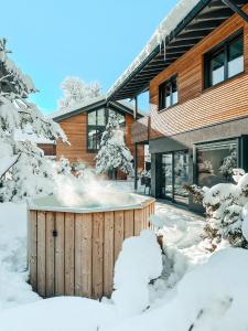 加尔米施-帕滕基兴ZSAM Chalets mit Sauna und Hottub的房屋前的雪地里有一个热水浴缸