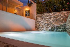 霍里顿Aeolos Hotel & Villas - Pelion的一个带石墙和浴缸的游泳池