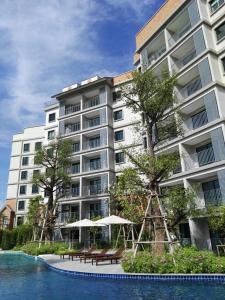 奈扬海滩The Residence @ Naiyang Beach by EHM的一座大型公寓楼,设有桌子和遮阳伞,毗邻游泳池