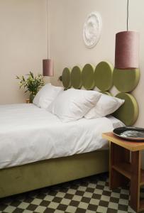 罗兹Hotel Pietryna的一间卧室配有一张带绿色床头板的床和一张桌子