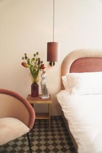 罗兹Hotel Pietryna的一间卧室配有一张床和一张花瓶桌子
