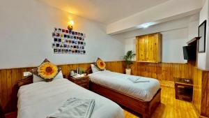 大吉岭Darjeeling Hillside Inn的一间酒店客房,设有两张床和电视