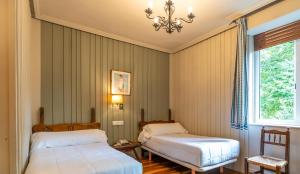 伊伦Hotel Alcazar Irun的一间卧室配有两张床和吊灯。