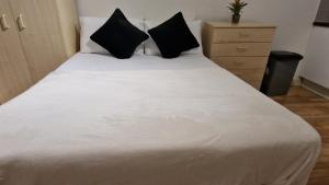 伦敦Compact living cosy studio flat in london的卧室配有带黑色枕头的白色床