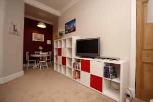 爱丁堡Hamish's Hame Edinburgh Licence No EH 69774 P的一间客厅,客厅里配有红色和白色的橱柜电视