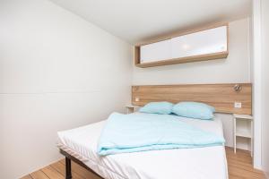 罗列特海岸Albatross Mobile Homes on Camping Cala Canyelles的一间卧室配有一张带蓝色床单的床和一扇窗户。