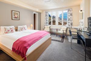 维尔德斯韦尔阿尔卑斯玫瑰酒店及花园的一间卧室配有一张大床、一张桌子和一张书桌