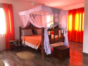 Kizungu翡翠湾度假村 的一间卧室配有华盖床和色彩缤纷的窗帘