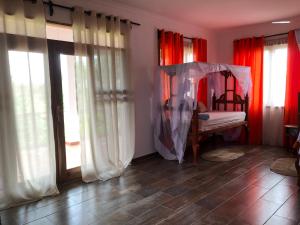 Kizungu翡翠湾度假村 的一间卧室配有红色窗帘和一张天蓬床