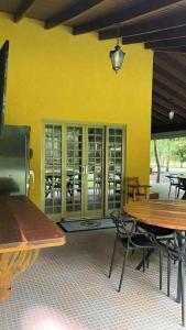 博尼图Rancho Jatobá的餐厅设有桌椅和黄色的墙壁
