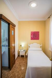 塞维利亚甜蜜的梦酒店的卧室配有白色的床,墙上挂有粉红色的画作