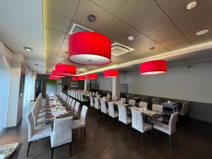 罗兹伊塞斯酒店的用餐室配有桌椅和红色吊灯。