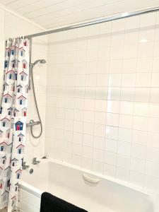 南塞尔尼Spinnaker Lodge · Cotswolds Lakeside Home的白色瓷砖浴室设有浴缸和淋浴帘