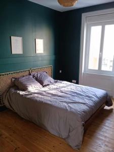 瑟堡Maison de ville quartier Pasteur的卧室内的一张床铺,卧室内有蓝色的墙壁