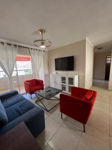 Los ParedonesStylish Stay Ciudad Juan Bosch的客厅配有蓝色的沙发和红色的椅子