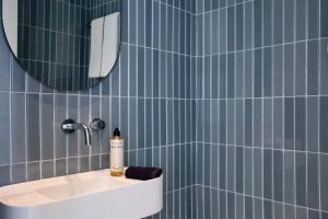 比雷埃夫斯Twinn Downtown Piraeus的蓝色瓷砖浴室设有水槽和镜子
